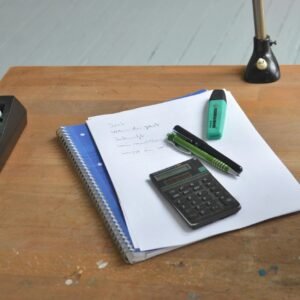 A neat workspace featuring a calculator, notebook, and stationery essentials on a wooden desk.