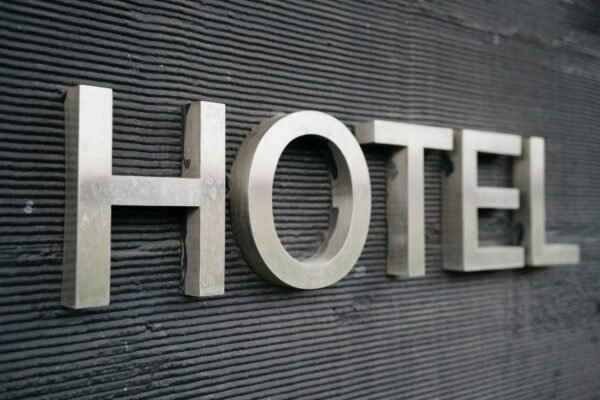 Close-up of a metallic hotel sign mounted on a textured wall.